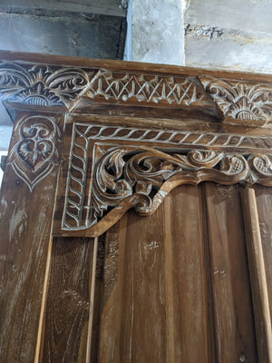 Hand-carved Balinese wooden door with intricate floral and geometric patterns
