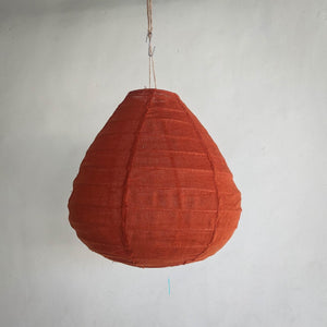Handcrafted Balinese orange fabric pendant lamp hanging against a neutral wall