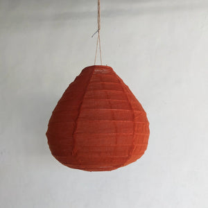 Handmade orange paper lantern hanging against a plain white wall