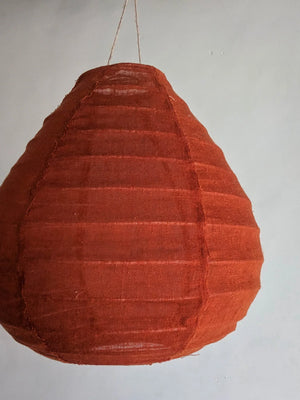 Handmade terracotta fabric pendant lamp hanging against plain wall, Balinese home decor