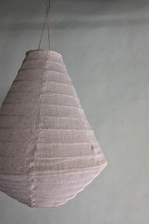 Handmade natural fiber pendant lamp with textured fabric shade against gray wall