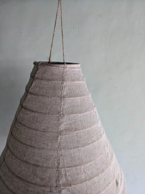 Handmade woven lampshade with natural fiber texture hanging against a neutral wall
