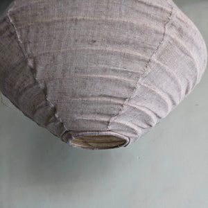 Handmade linen lampshade with natural texture against a light grey wall