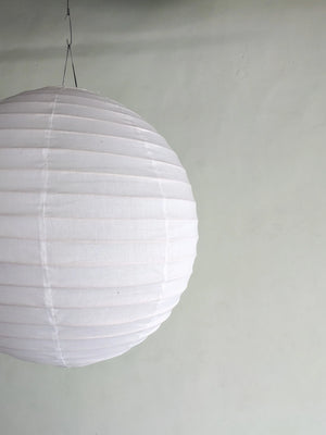 Large white paper lantern hanging against a plain light wall, minimalist home decor