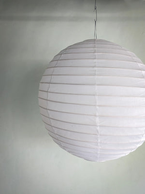 White paper lantern ceiling light with ribbed texture against a plain wall