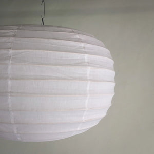 Large white paper lantern chandelier with ribbed texture hanging indoors