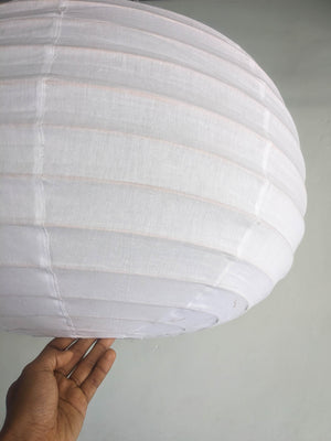 Hand holding large white fabric lantern against a plain wall, minimalist home decor