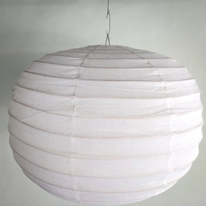 Round white paper lantern pendant light with ribbed texture, hanging against a plain wall.