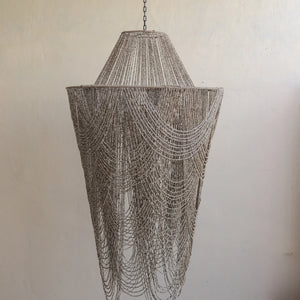 Handmade Balinese pearl bead chandelier with draped strands against a neutral wall