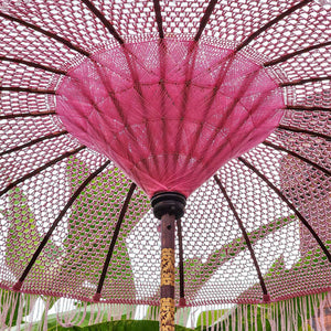 Handmade pink macrame parasol with carved wooden pole, outdoor garden decor