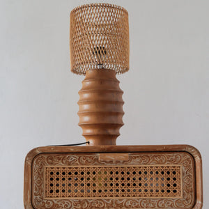 Handcrafted rattan lamp with woven shade on carved wooden furniture, boho home decor