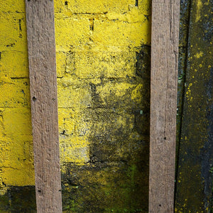 Reclaimed teak wood mirror frame with rustic texture against a yellow brick wall