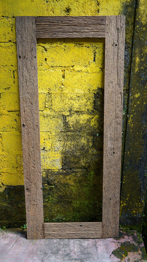 Reclaimed teak wood mirror frame with rustic texture against a yellow brick wall