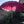 Large pink Balinese ceremonial umbrella with gold accents in a tropical garden setting