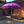 Purple Balinese umbrella with gold accents in front of hand-carved wooden entrance