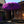 Purple Balinese parasol with fringe in front of carved wooden door and traditional architecture