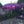 Purple Balinese parasol with fringe and gold accents in a garden courtyard
