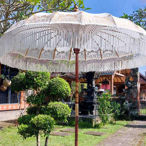 Hand-carved Balinese parasol with fringe in tropical garden, traditional decor, outdoor setting