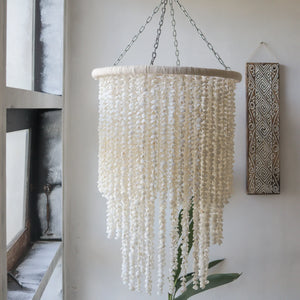 Handmade Balinese seashell chandelier hanging in a bright, minimalist room.