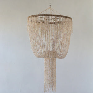 A beige seashell chandelier with a jelly fish design hanging against a neutral background.