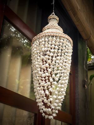 Handmade Balinese seashell hanging lamp with intricate beaded shell design outdoors