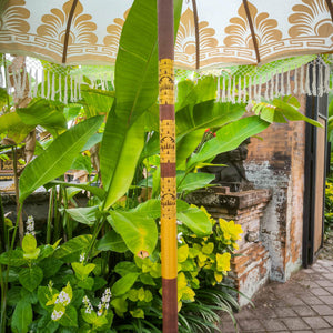 Hand-carved Balinese parasol with gold accents in tropical garden setting