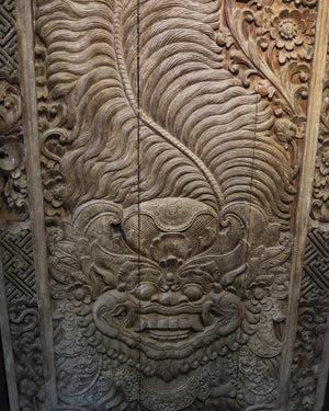 Hand-carved Balinese wooden wall panel with intricate floral and mythical face details