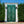 Green hand-carved Balinese vintage door gate with intricate patterns in outdoor garden.