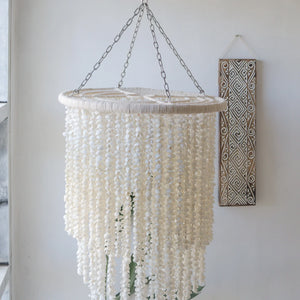 Handmade white seashell chandelier hanging in a bright, minimalist room