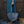 Person holding a textured handbag with a cat in the foreground, wooden door in the background