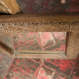 Hand-carved wood mirror frame with intricate geometric patterns on rustic background