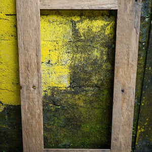 Rustic reclaimed wood mirror frame with bohemian style against a yellow textured wall