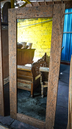 Rustic reclaimed wood decorative mirror with wide frame, reflecting wooden benches.