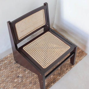 Handcrafted wooden dining chair with woven rattan seat and backrest on textured rug