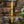Hand-carved wooden stick with gold Balinese patterns against brick wall