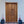 Hand-carved Balinese wooden door with intricate floral motifs and potted pink flowers