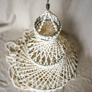 Handmade beaded seashell chandelier with layered design on a neutral background.