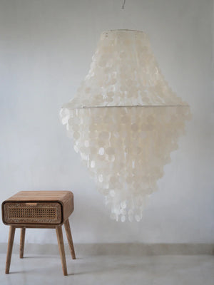 Bohemian capiz shell chandelier with wooden bedside table in a minimal room