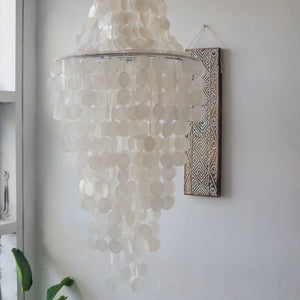 Capiz shell chandelier with white natural discs hanging in a minimalist interior room
