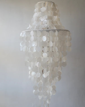 white capiz shell chandelier with cascading natural shells hanging against a neutral wall