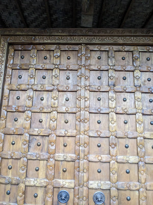 Hand-carved Balinese wooden door with intricate geometric patterns and metal accents