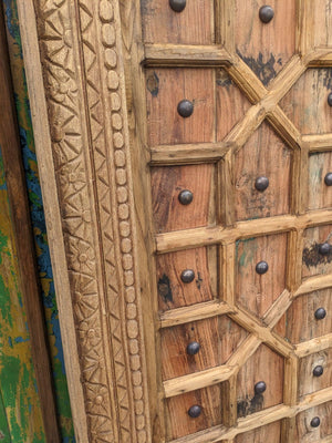 Hand-carved wooden door with intricate geometric and floral patterns, rustic finish