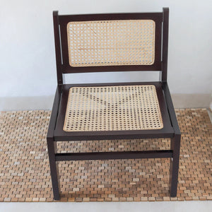 Handcrafted wooden chair with rattan cane seat and backrest on woven mat