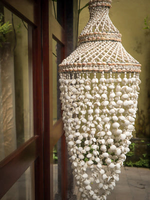 Handmade seashell chandelier mobile with intricate shell patterns in a natural outdoor setting