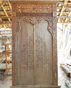 Hand-carved Balinese teak wood door with intricate floral and scrollwork patterns