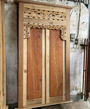 Hand-carved Balinese wooden door with intricate floral and geometric patterns