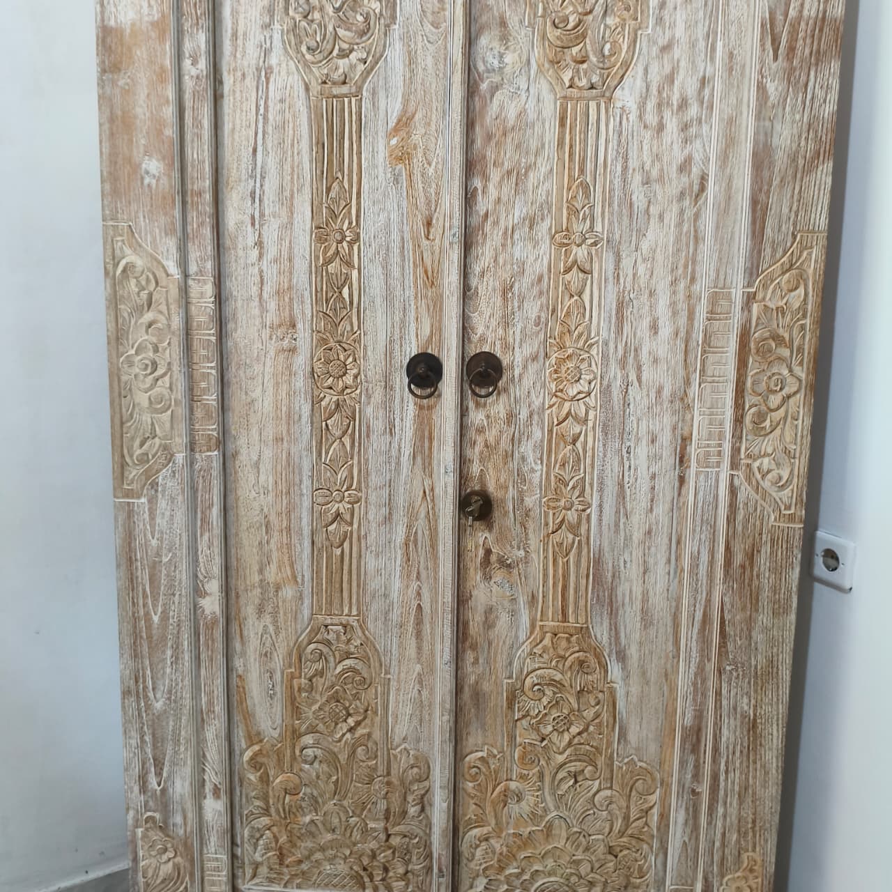 Wooden door with intricate carvings and two handles on a white background