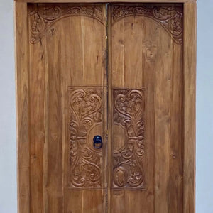 Hand-carved Balinese wooden door with intricate floral patterns and ornate detailing