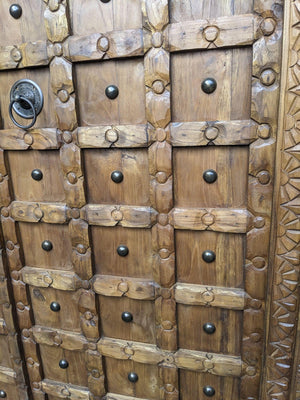 Hand-carved wooden door with geometric patterns and metal ring handle, Balinese home decor.