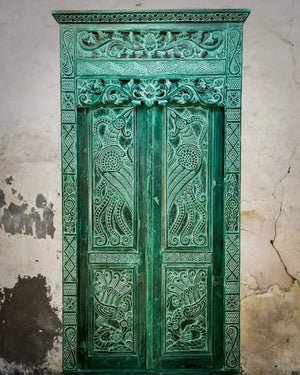 Green vintage hand-carved Balinese wooden door with intricate floral designs
